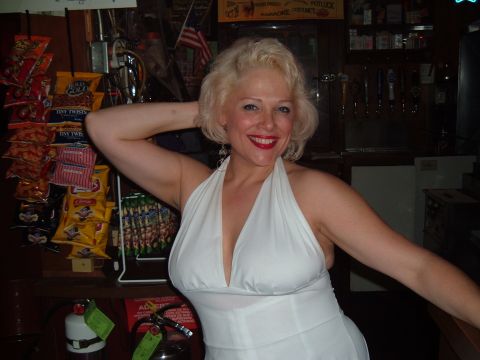 1989 Ford Bronco - Woman in a white dress poses in a bar setting with snack displays behind her.