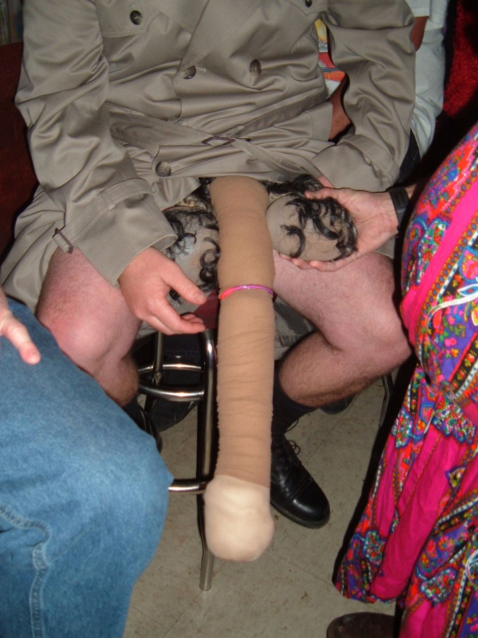 Person in trench coat with prosthetic limb covered in tan fabric and hair.