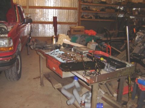 1992 Ford Bronco - A red 1992 Ford Bronco is parked in a garage, with its hood up and tools laid out on a workbench.