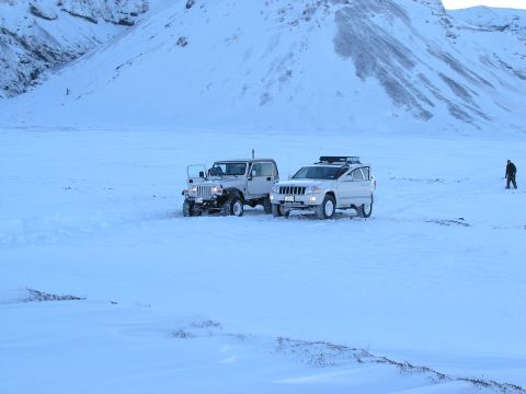 2001 Jeep Wrangler - Two SUVs are stopped in a vast, snow-covered area with a person visible in the distance.