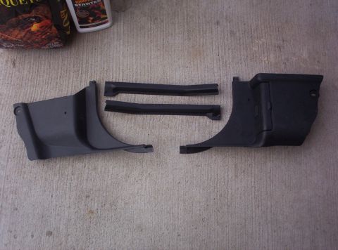 1994 Ford Probe - Several black plastic interior trim pieces and rubber seals are displayed on a concrete surface, with a bag and bottle visible behind them.