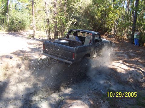1987 Ford Bronco - Ford Bronco navigating a dirt trail with a spare tire in the bed.
