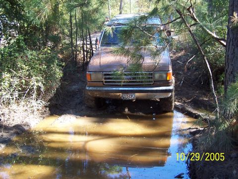 1987 Ford Bronco - A 1987 Ford Bronco navigates a muddy obstacle on an off-road trail.