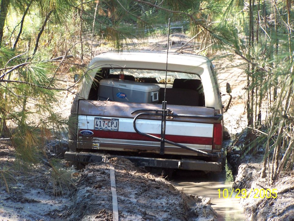 1987 Ford Bronco stuck in mud, rear view, brown and white exterior, license plate 417-CPJ