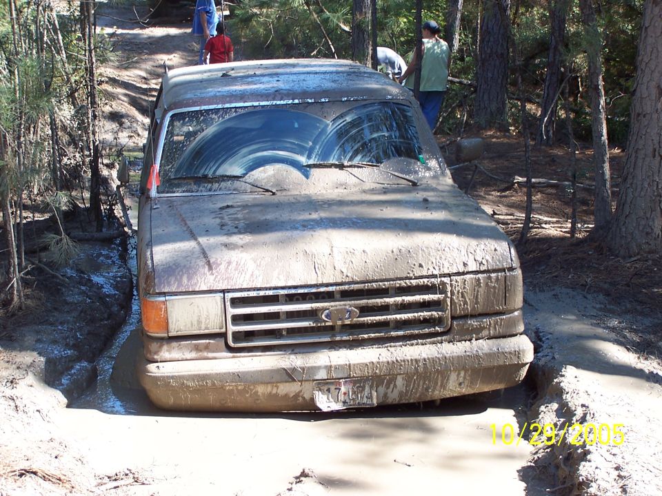 Mud-covered 1987 Ford Bronco stuck in a muddy ditch, front view