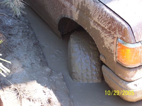 1987 Ford Bronco - Vehicle stuck in mud, showing front wheel and fender detail.