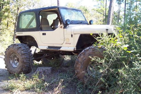 1987 Ford Bronco - This modified Jeep Wrangler sits off-road, equipped with oversized tires and a lifted suspension system.