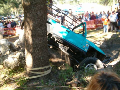 1991 Ford Bronco - An off-road vehicle attempts to navigate a challenging obstacle course, getting stuck against a tree.