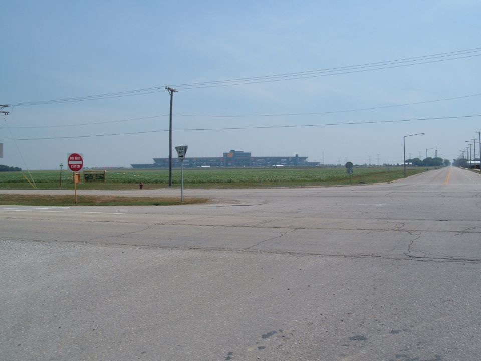 Empty rural road intersection with Do Not Enter sign and a distant stadium on the horizon