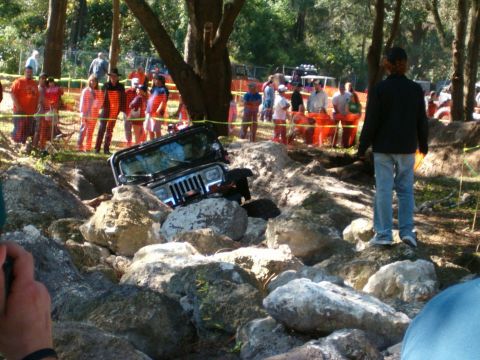 1991 Ford Bronco - A black Jeep Wrangler is stuck in a rocky ditch during an off-road event.