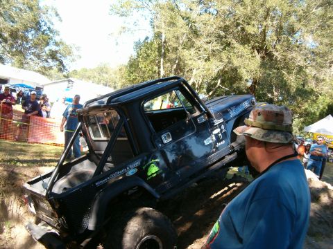 1991 Ford Bronco - A modified Jeep CJ-7 navigates an off-road course with spectators watching.