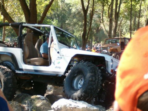1991 Ford Bronco - White Jeep Wrangler tackling rocks with another Jeep in the background.