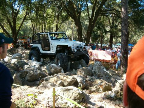1991 Ford Bronco - A modified Jeep Wrangler tackles a challenging rock crawling course during an event.