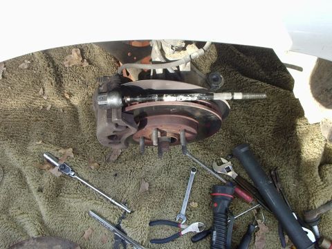 2000 Ford Taurus - Tools are laid out on a blanket next to a disassembled car brake and axle assembly.