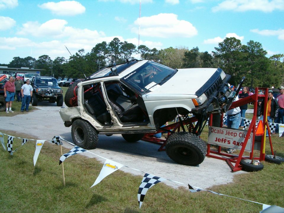 White Jeep Grand Cherokee with doors removed, lifted on a red frame with large tires