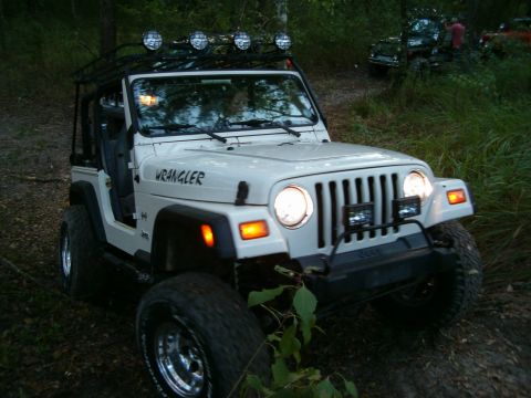 1991 Ford Bronco - White Jeep Wrangler on a wooded trail with another Jeep in the background.