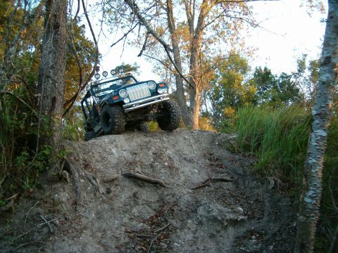 1991 Ford Bronco - This modified Jeep Wrangler navigates a steep, wooded incline during an off-road excursion.