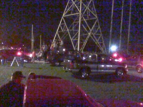 1986 Ford Bronco - A silver pickup truck is parked near a large metal tower at night.