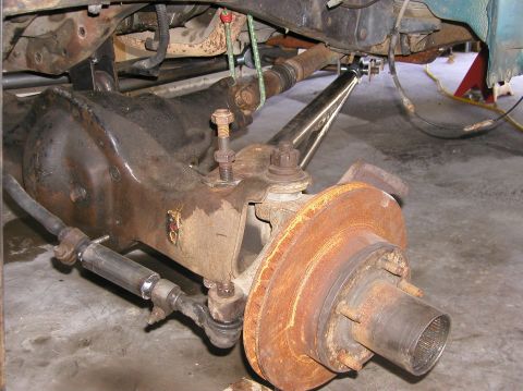 1984 Ford Bronco - Close-up of a vehicle's front axle and suspension system, showing brake rotor and steering components.