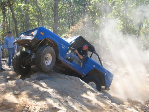 1990 Ford Bronco - Blue Ford Bronco navigating a difficult rocky terrain during an off-road excursion.