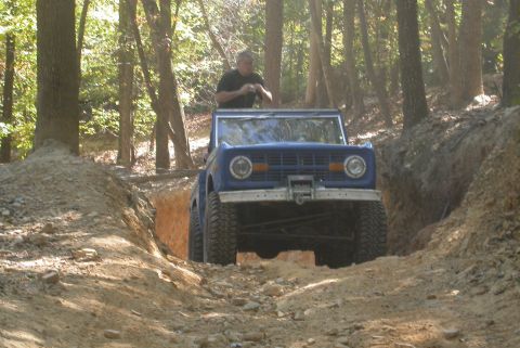 1990 Ford Bronco - A blue 1970 Ford Bronco navigates a challenging off-road trail.