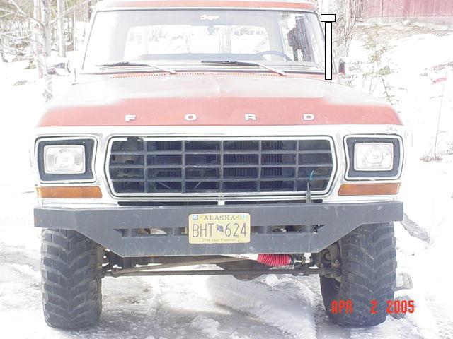 Lifted orange-red Ford truck front view in snow with Alaska plate BHT 624
