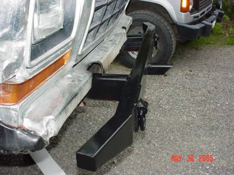 1978 Ford Bronco - Close-up of a 1978 Ford Bronco's front end, showing a custom tow hitch attached to the bumper, with another vehicle visible in the backgrou…
