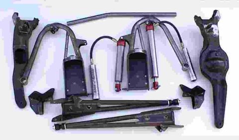 1984 Ford Bronco - A collection of automotive suspension parts, including shocks labeled 'race-runner', are arranged on a white surface.