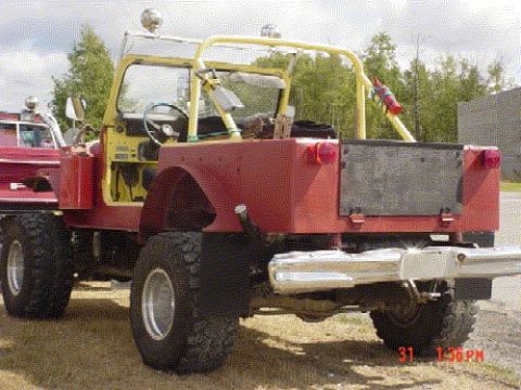 1976 Jeep CJ7 - Rear view of a modified 1976 Jeep CJ7 with a yellow roll cage and large off-road tires.