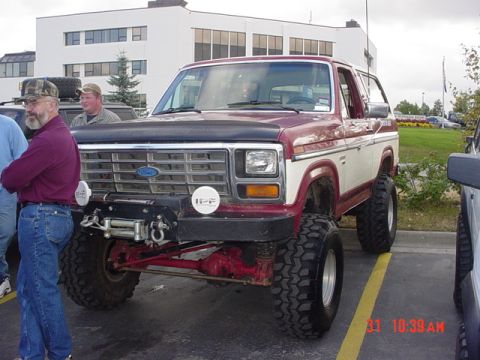 1976 Jeep CJ7 - Maroon and white Ford Bronco parked in a lot, with two men standing next to it.