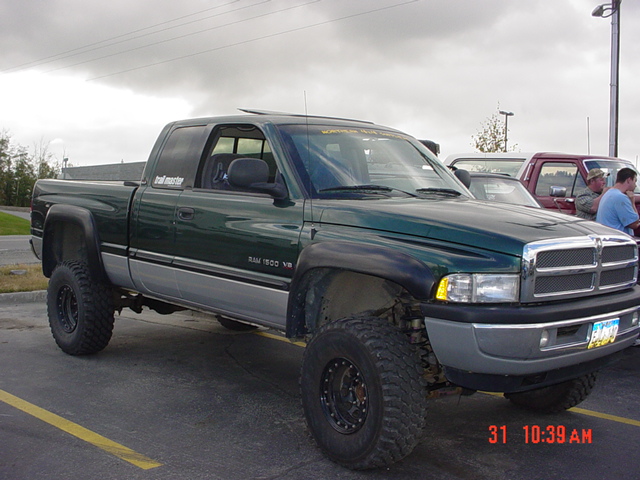 Green pickup truck with lifted suspension and off-road tires, viewed from a 3/4 front angle