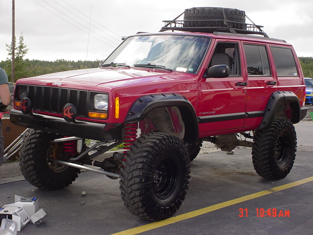 Red lifted Jeep Cherokee with large tires and roof rack