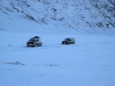 2001 Jeep Wrangler - Two SUVs navigate a snow-covered terrain, with a mountainous backdrop suggesting a remote or challenging environment.