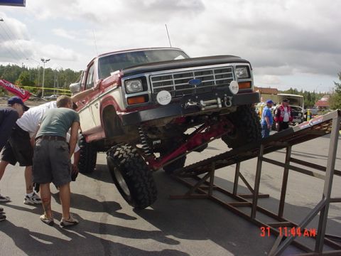 1976 Jeep CJ7 - Customized 1980 Ford F-Series truck being displayed on ramps at an event.