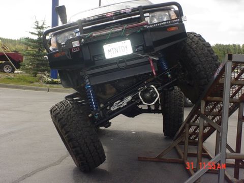 1976 Jeep CJ7 - This heavily modified SUV is positioned at an angle on a metal ramp, displaying its off-road capabilities.
