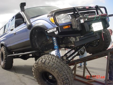 1976 Jeep CJ7 - Modified blue pickup truck with snorkel and off-road tires is positioned on a ramp.