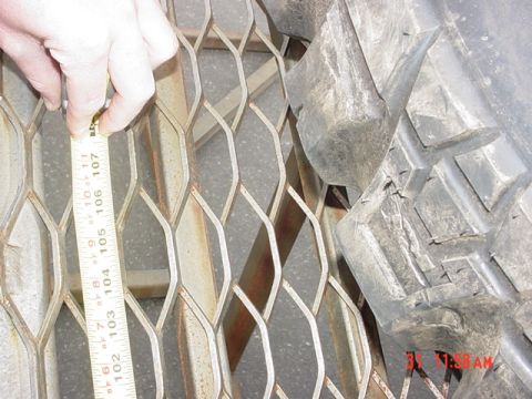 1976 Jeep CJ7 - A close-up shot shows a tape measure being used to gauge the depth of a tire's tread against a diamond-patterned metal grate.