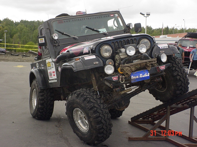 Black Jeep CJ with off-road tires on a ramp, "Team Alaska" sticker visible