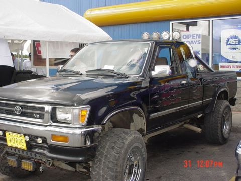 1976 Jeep CJ7 - This modified Toyota pickup truck is parked in front of a building with yellow trim and an ASE sign.