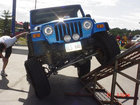 1976 Jeep CJ7 - A blue Jeep Wrangler is positioned on a metal ramp, with its front wheels elevated.