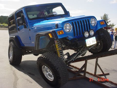 1976 Jeep CJ7 - Blue Jeep Wrangler on a ramp, showing its lifted suspension and off-road tires.