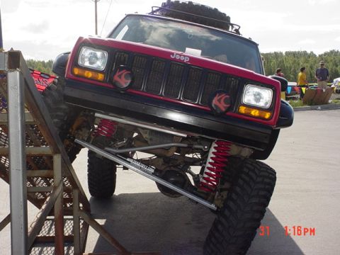 1976 Jeep CJ7 - A modified Jeep Cherokee XJ is positioned on a metal ramp, its suspension and off-road tires.