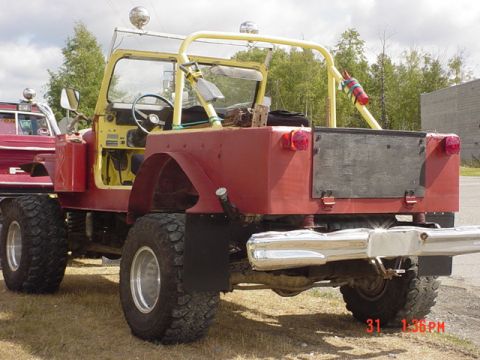 1976 Jeep CJ7 - This heavily modified Jeep features a custom roll cage and oversized tires, with another vehicle parked alongside.