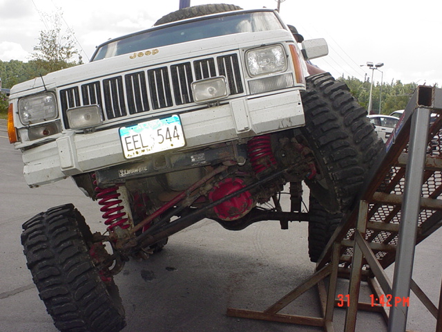 White Jeep Cherokee XJ with large tires on a ramp