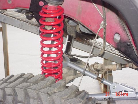 1976 Jeep CJ7 - Close-up of a vehicle's suspension system, showing a red coil spring and linkage.