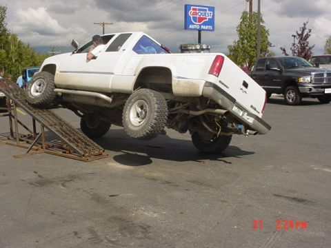 1976 Jeep CJ7 - A modified pickup truck is shown on a ramp, with a Carquest Auto Parts sign in the background.