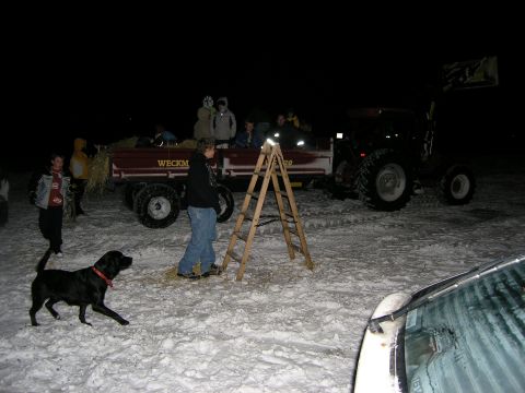 2001 Jeep Wrangler - A tractor pulls a wagon filled with people through a snowy field at night, with a dog and a ladder nearby.