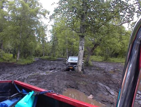 1978 Ford Bronco - Off-road vehicle navigating a very muddy trail in a wooded area.