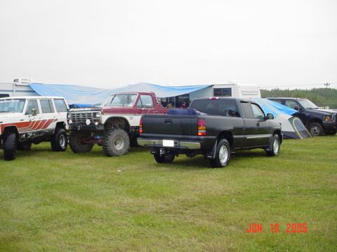 1978 Ford Bronco - A collection of off-road vehicles, including a lifted 1978 Ford Bronco, are parked on a grassy field next to a tent and RV.