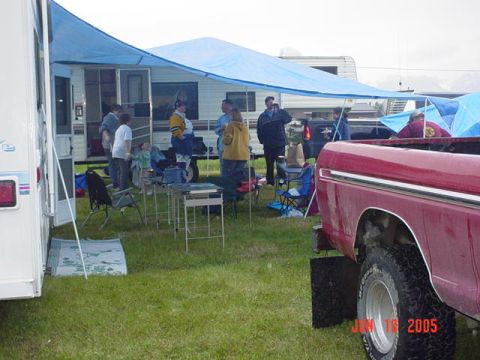 1978 Ford Bronco - A red pickup truck is parked at an outdoor gathering with RVs and people.